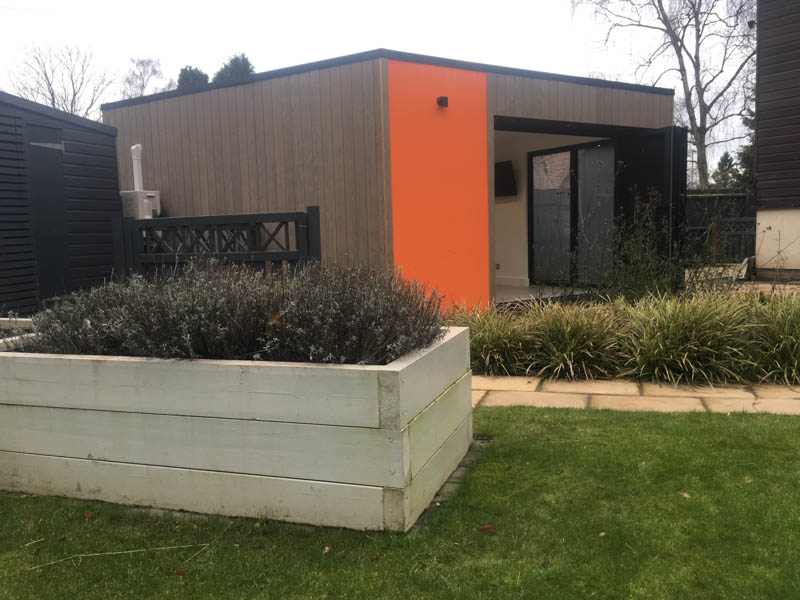 The orange render is mixed with timber cladding on this garden room