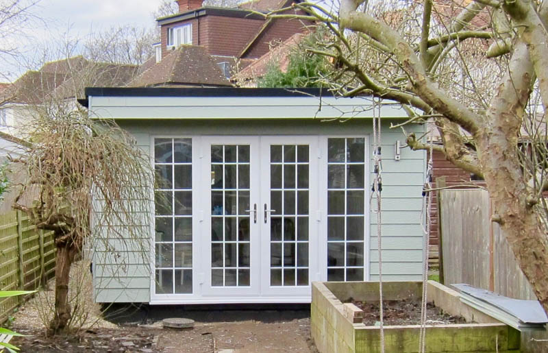 Exterior of the garden office with green Cedral cladding and Georgian style French doors