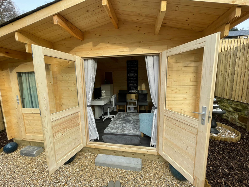 looking Inside an insulated log cabin office by Hargreaves Garden Spaces