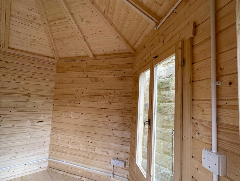 Inside a hexagonal insulated log cabin by Hargreaves Garden Spaces