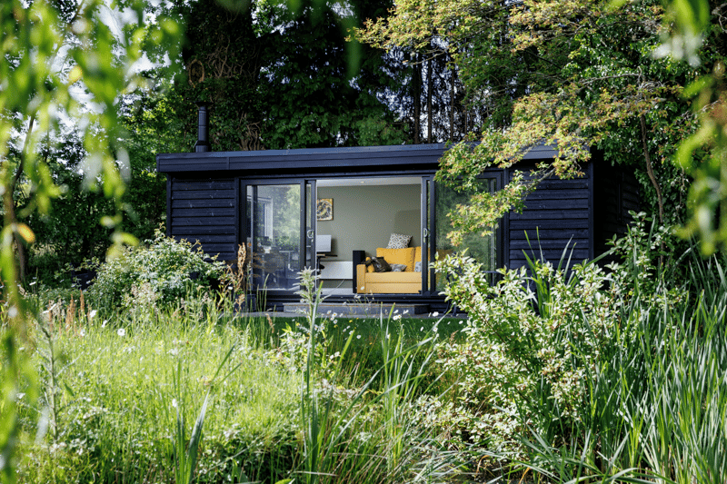 The black clad garden office sits well in the colours of the garden