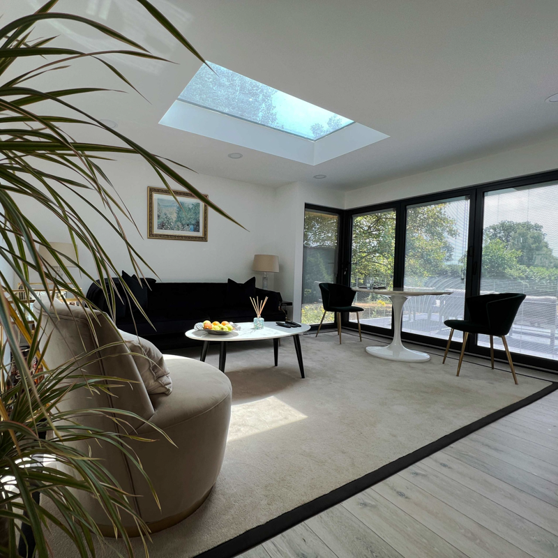 The main living space features wrap-around glazing and a large skylight