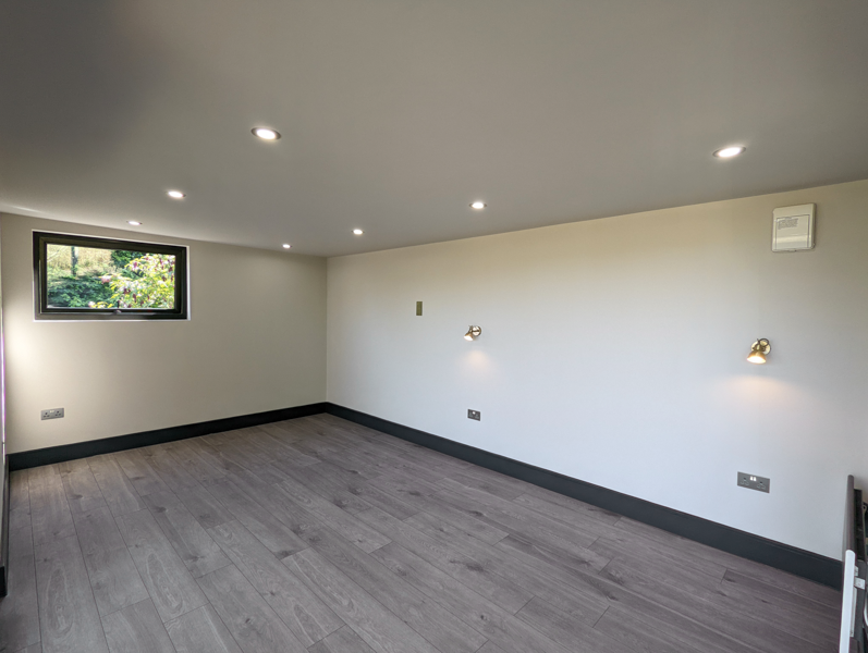 Plastered and decorated interior with grey laminate flooring and black skirting