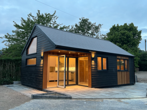 Bespoke pitched roof garden annexe with slate roof, black cement board cladding and Western Red Cedar details