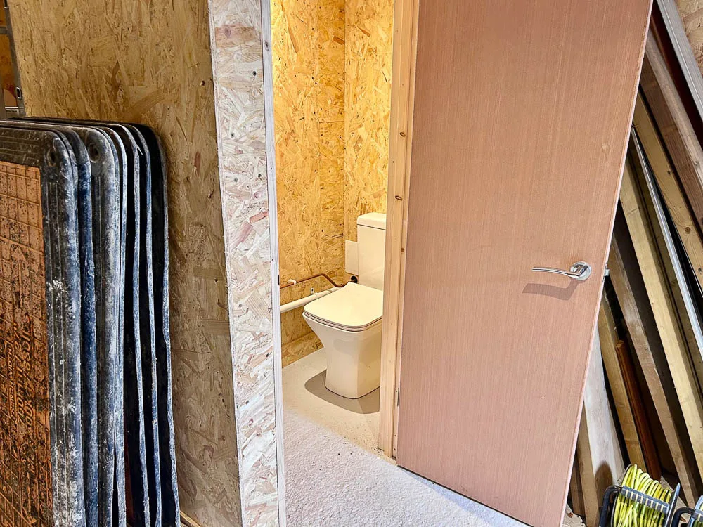 A cloak room with toilet and washbasin sits in the corner of the garage