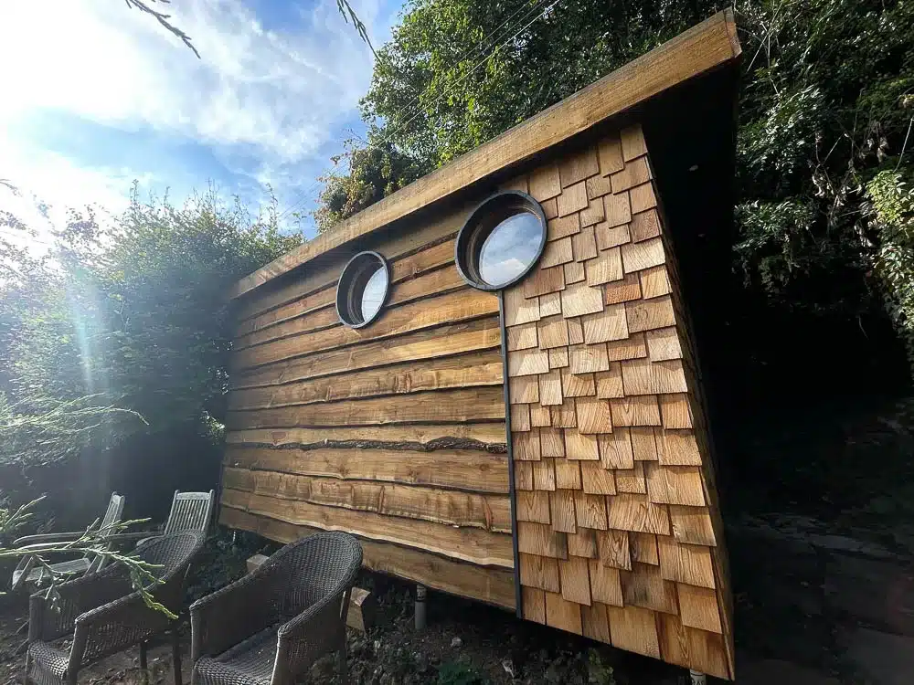 Exterior of a Rustic Realities garden room with waney edge cladding and cedar shingles