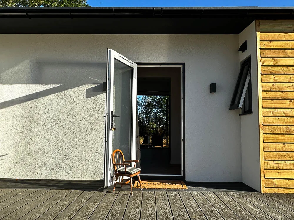 The front door sits in a recessed porch area which has been rendered white