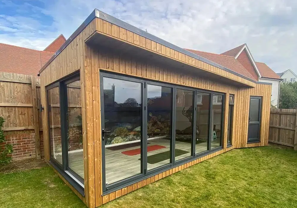 2.8m tall garden gym by Ark Design Build which has angled walls following the boundary walls of the garden