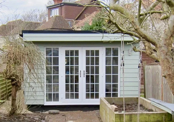 Exterior of the garden office with green Cedral cladding and Georgian style French doors