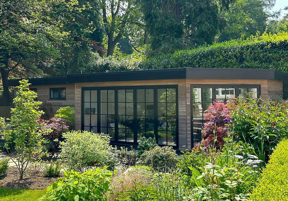 The larch clad garden room blends into the lovely garden